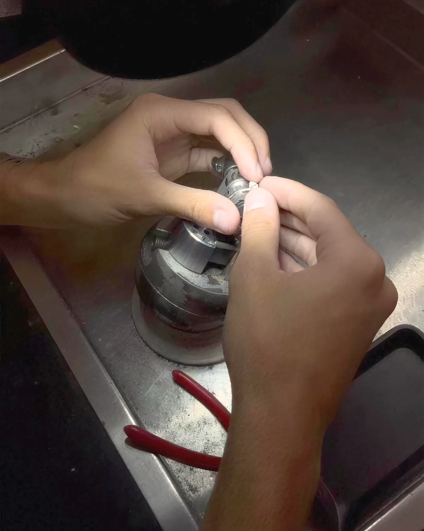 The goldsmith's hands setting a diamond ring at the workbench in the DAZZ casting workshop
