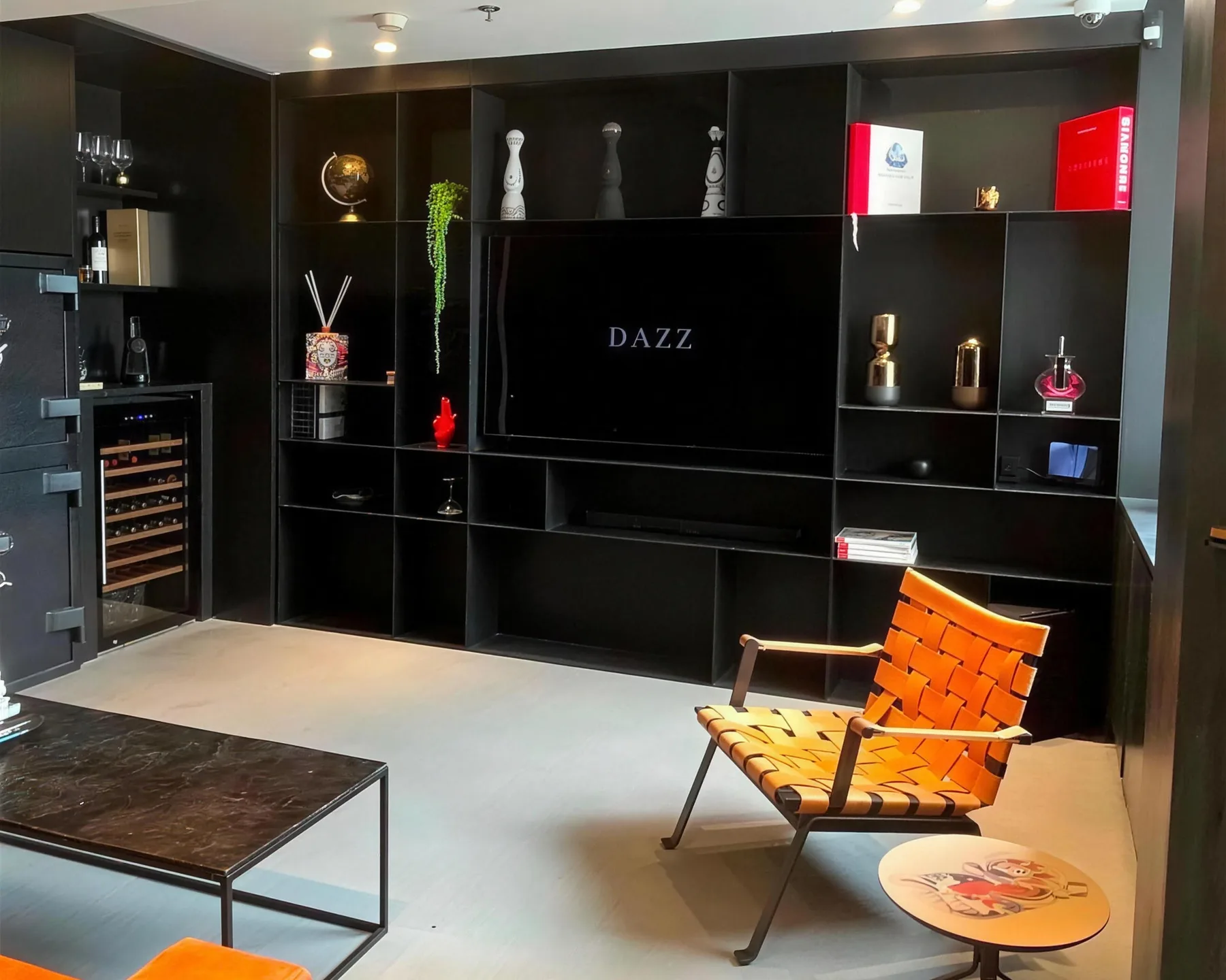 The lounge area at the DAZZ offices at the Israel Diamond Exchange, Ramat Gan — a black bookcase, an armchair and a screen with the DAZZ logo